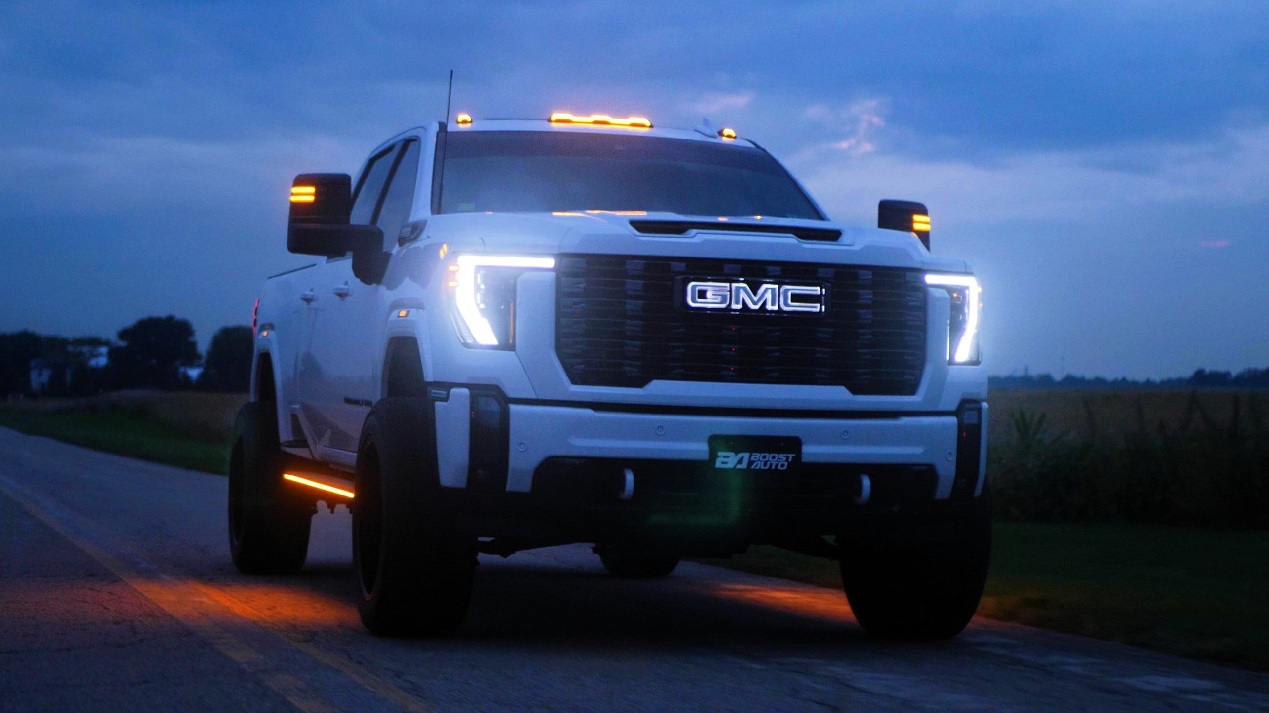 White 2024 GMC 3500 with Boost Auto S-Series Cab Lights, Lumastep M2 Running Boards, Fender Lights, and Tow Mirror Lights lit up in white running light.