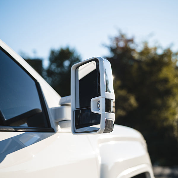 White truck with Boost Auto Mirrors showing the glass side from an angle outside during the day